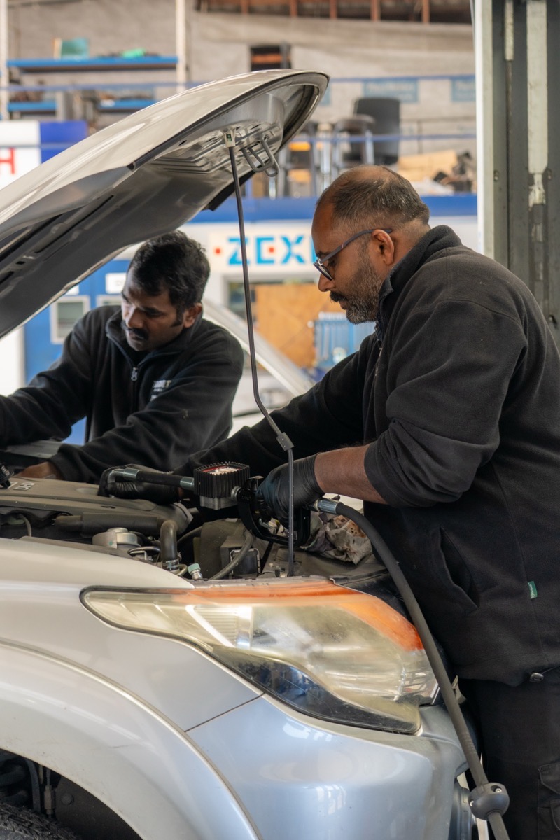 Two Turbo & Diesel technicians working under the bonnet of an SUV in the workshop.