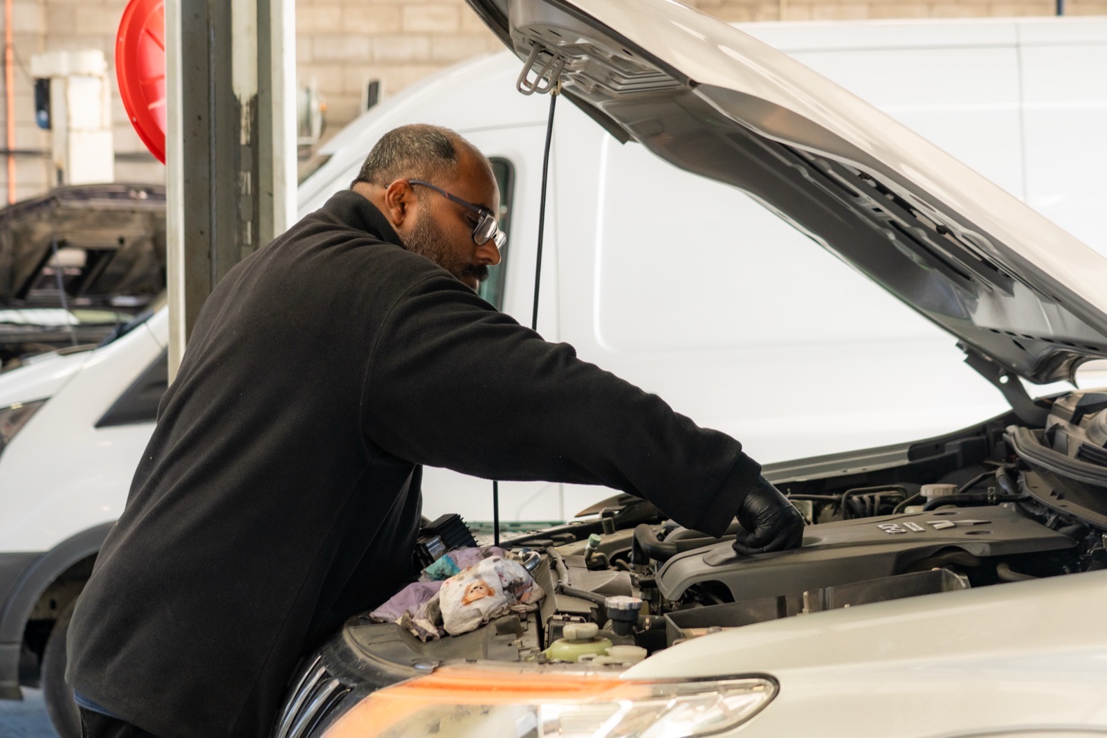 Turbo & Diesel mechanic working in the engine bay of a white commercial van.