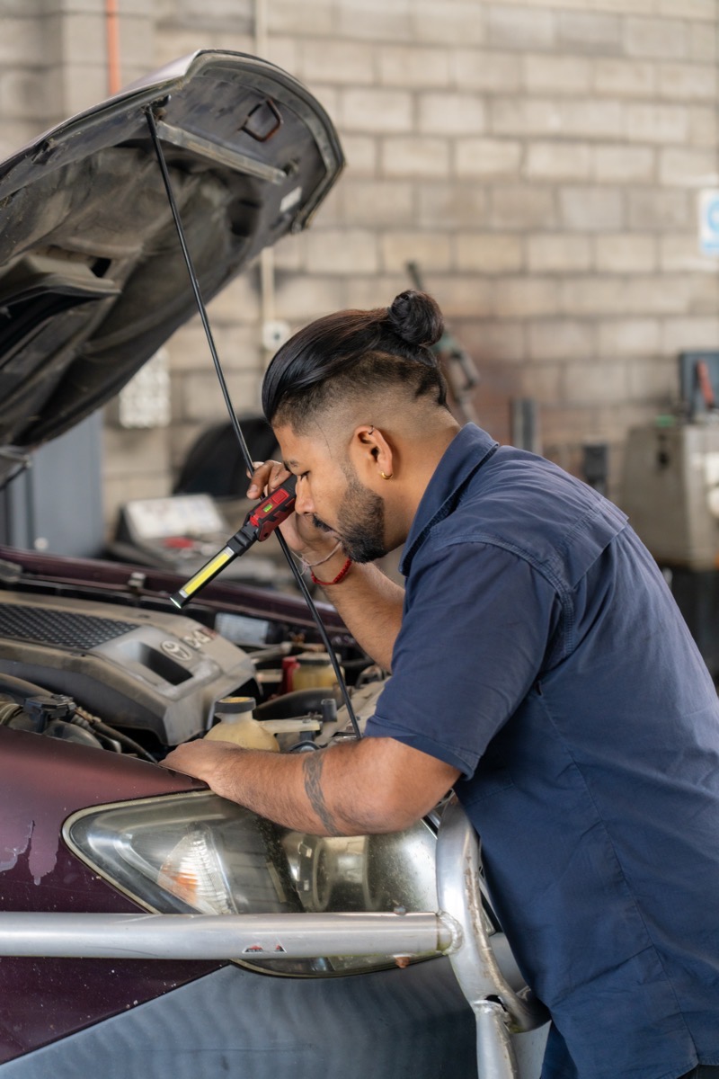 Technician inspecting an engine bay under lamp light during a diesel inspection.