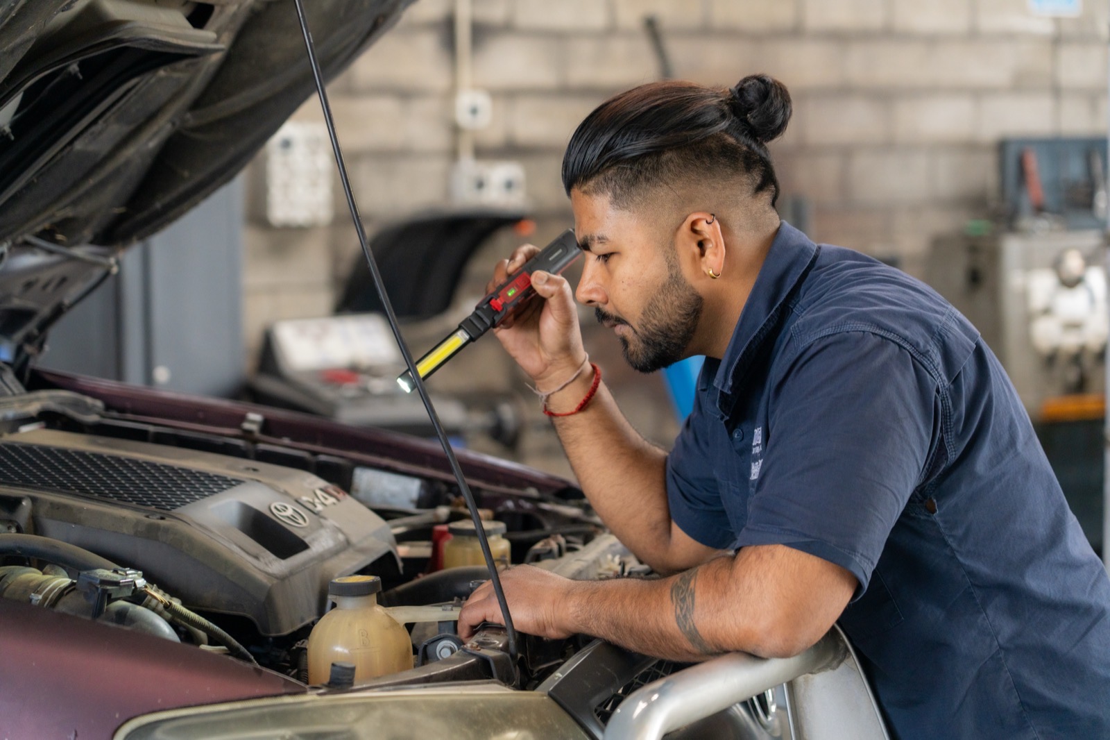 Mechanic inspecting an engine bay under lamp light at the Turbo & Diesel workshop.