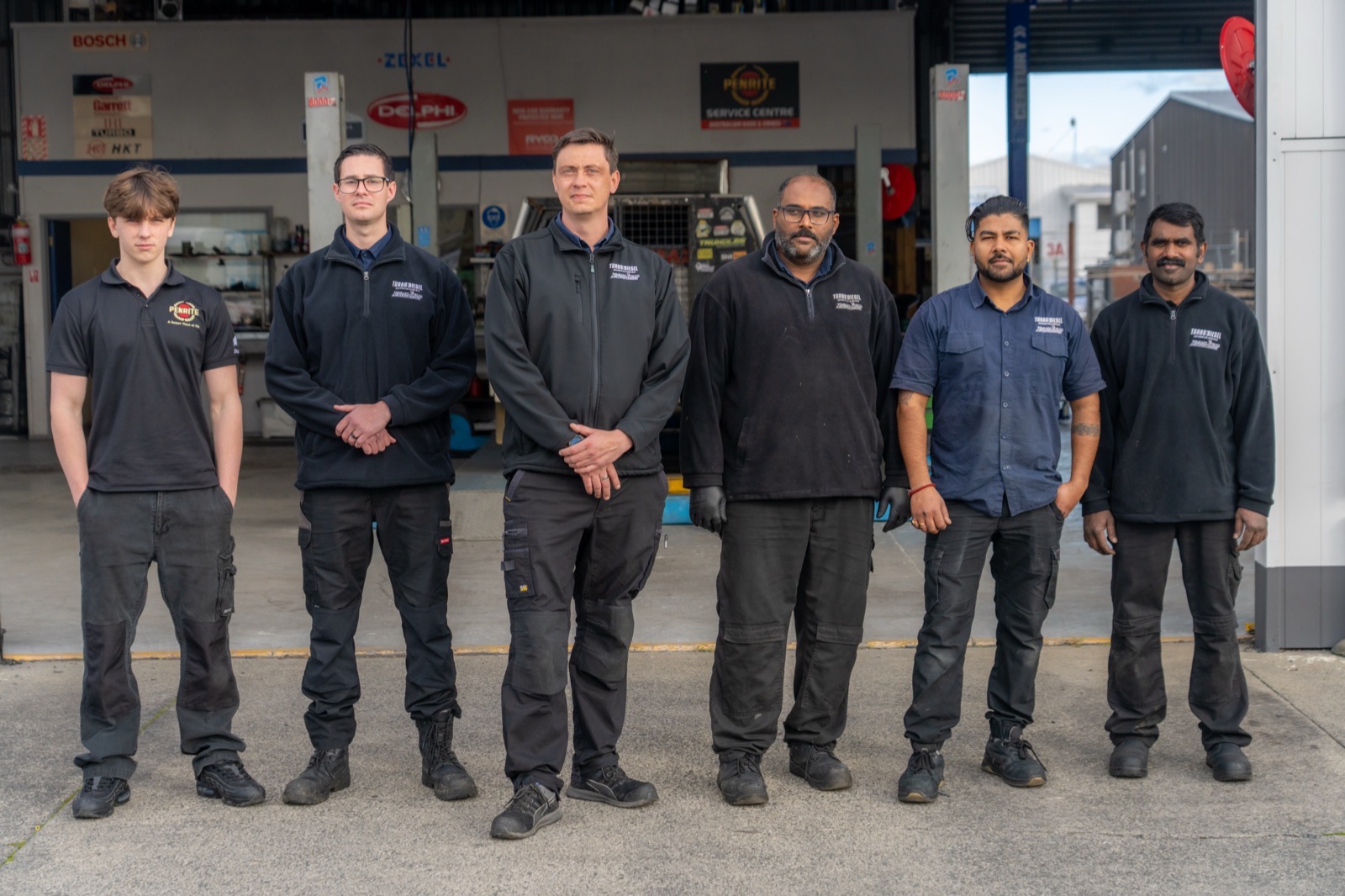 The Turbo & Diesel team lined up at the workshop entrance beneath the Bosch, ZEXEL and Delphi signage.