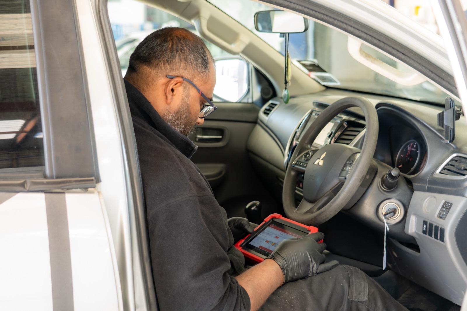 Technician monitoring live data on a diagnostic scan tool from the cab of a Mitsubishi ute.