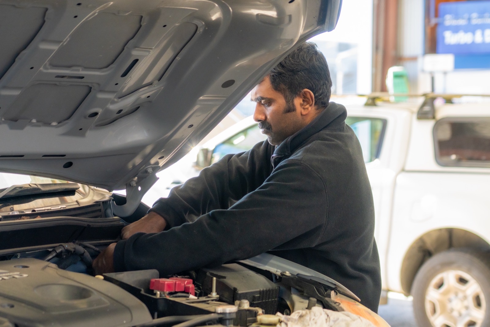 Technician working in the engine bay of a diesel ute at the Turbo & Diesel workshop.