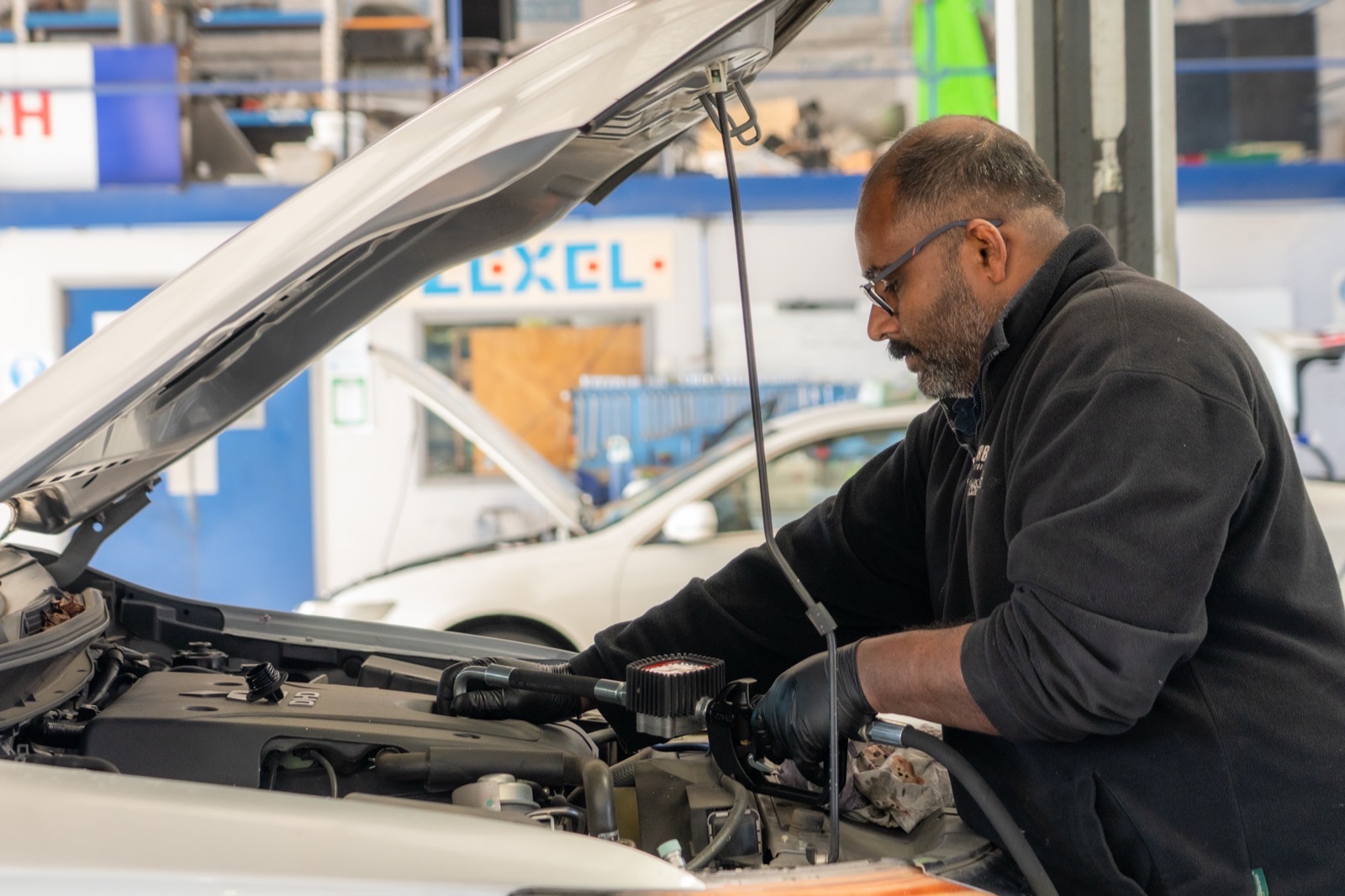Diesel technician running diagnostics beside the ZEXEL diesel injection signage in the workshop.